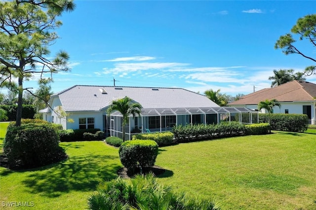 back of property with glass enclosure, a tiled roof, and a yard