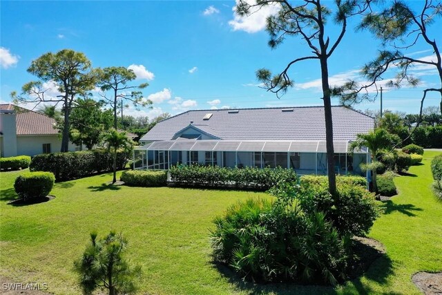 rear view of property with a lawn and a tile roof