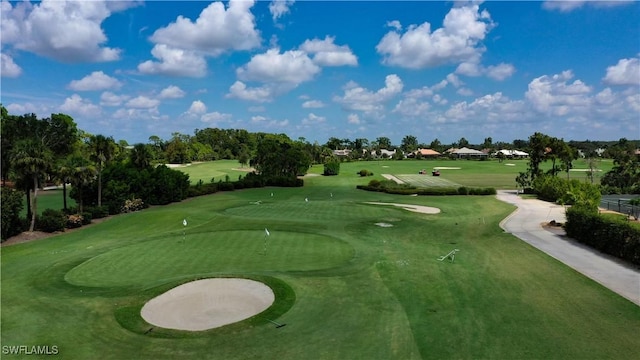 view of property's community featuring view of golf course and a yard