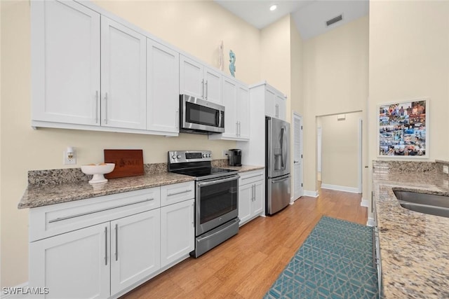 kitchen featuring appliances with stainless steel finishes, light wood-style flooring, visible vents, and white cabinetry