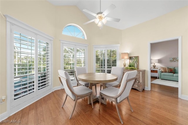 dining space featuring high vaulted ceiling, baseboards, ceiling fan, and light wood finished floors