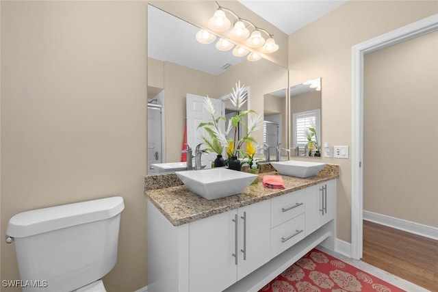 bathroom featuring wood finished floors, a sink, toilet, and baseboards