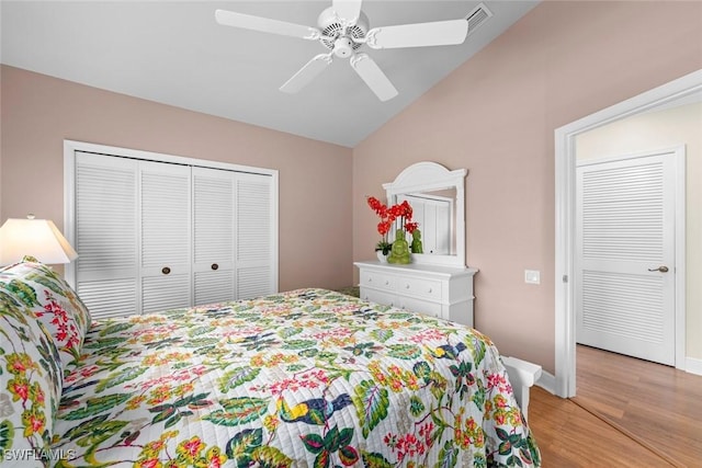 bedroom with a closet, light wood-style flooring, a ceiling fan, vaulted ceiling, and baseboards