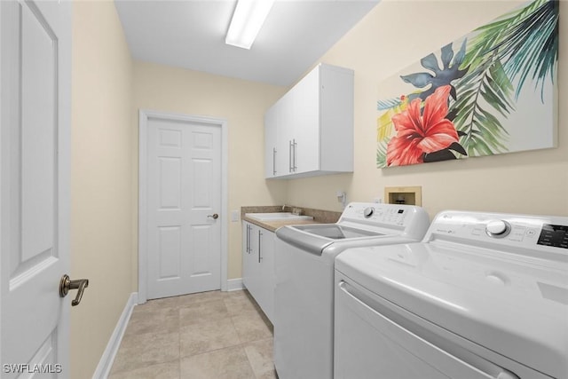 washroom with cabinet space, light tile patterned floors, baseboards, washer and clothes dryer, and a sink