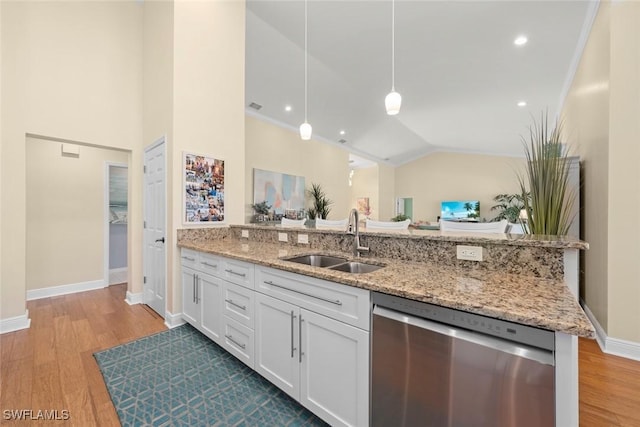 kitchen with wood finished floors, decorative light fixtures, stainless steel dishwasher, white cabinetry, and a sink