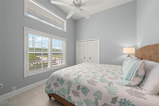 bedroom featuring a ceiling fan, baseboards, a closet, and a towering ceiling