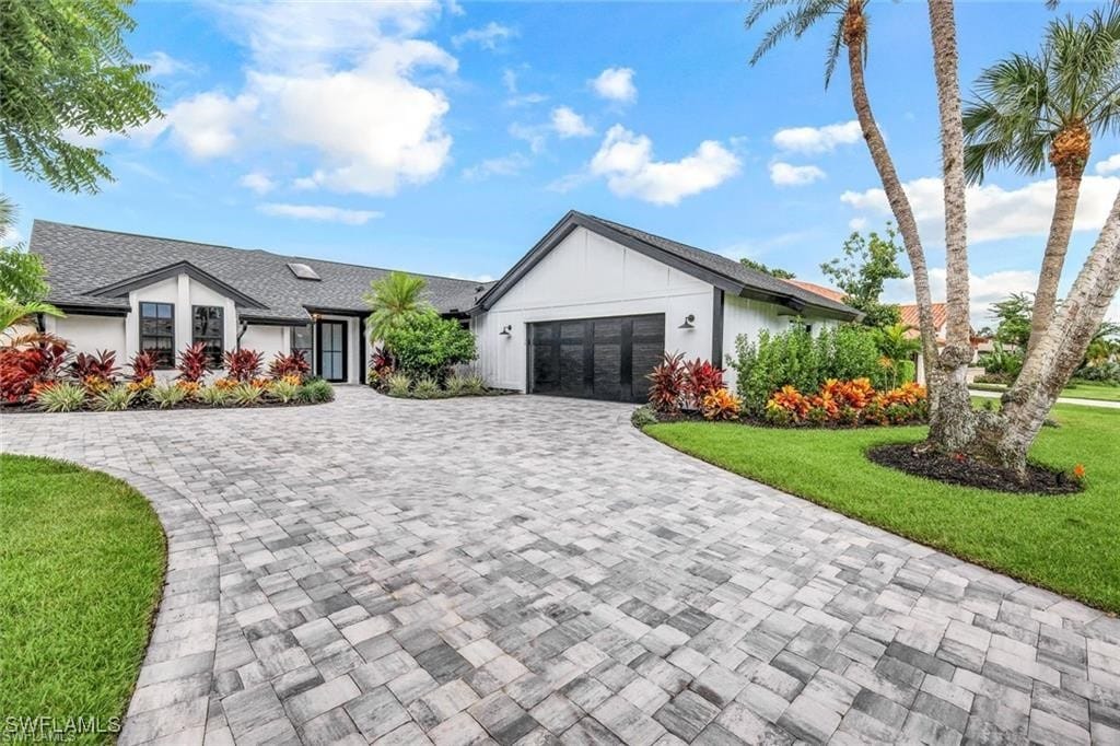 view of front of home with a front lawn, decorative driveway, and an attached garage