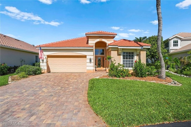 mediterranean / spanish-style home with a garage, a tile roof, decorative driveway, stucco siding, and a front lawn