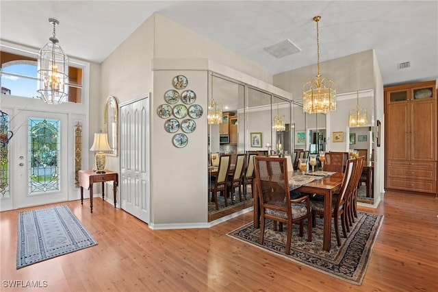 dining space with a chandelier, visible vents, a high ceiling, and wood finished floors