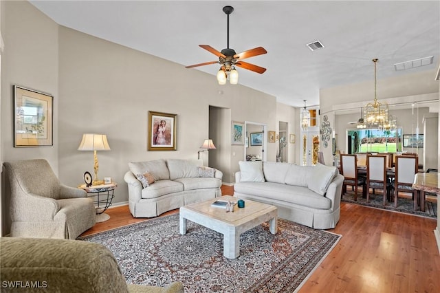 living area with ceiling fan with notable chandelier, visible vents, and wood finished floors