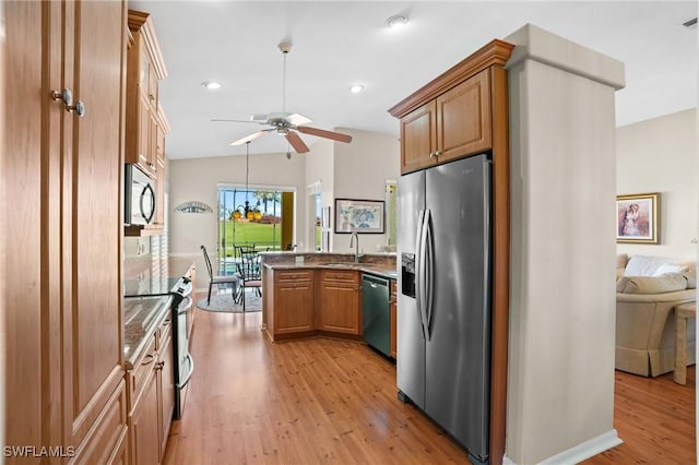 kitchen with light wood finished floors, stainless steel appliances, vaulted ceiling, a sink, and a peninsula