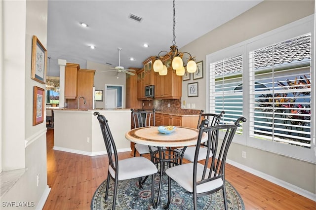 dining room with light wood-style floors, visible vents, baseboards, and ceiling fan with notable chandelier