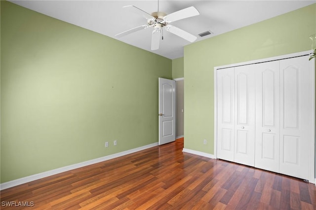 unfurnished bedroom featuring a closet, visible vents, ceiling fan, wood finished floors, and baseboards