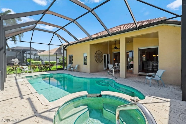 view of pool with glass enclosure, a patio, ceiling fan, and a pool with connected hot tub