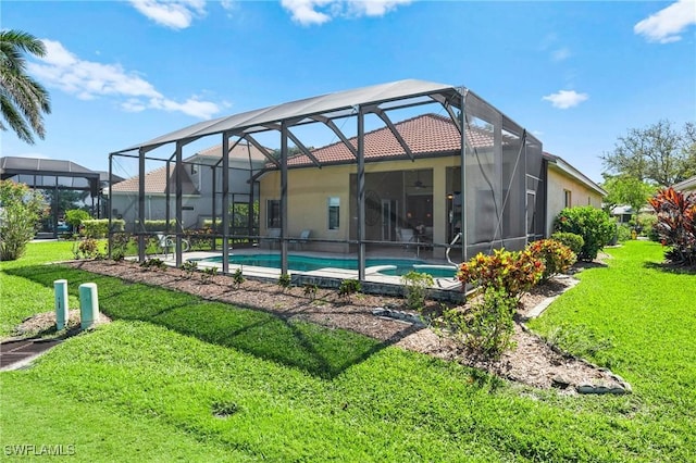 rear view of house featuring a lawn, a lanai, and an outdoor pool