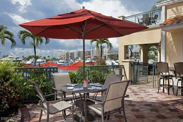 view of patio with a balcony, a view of city, and outdoor dining area