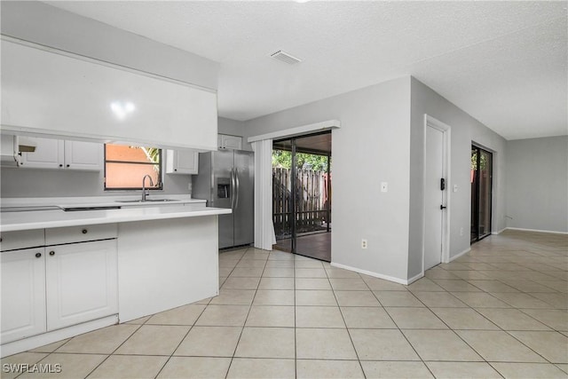 kitchen featuring light countertops, visible vents, light tile patterned flooring, a sink, and stainless steel fridge