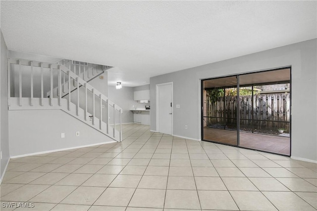 tiled empty room featuring baseboards, stairway, and a textured ceiling