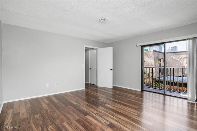 spare room featuring baseboards, a textured ceiling, visible vents, and wood finished floors