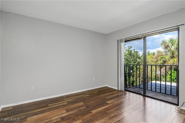 spare room featuring a textured ceiling, baseboards, and wood finished floors