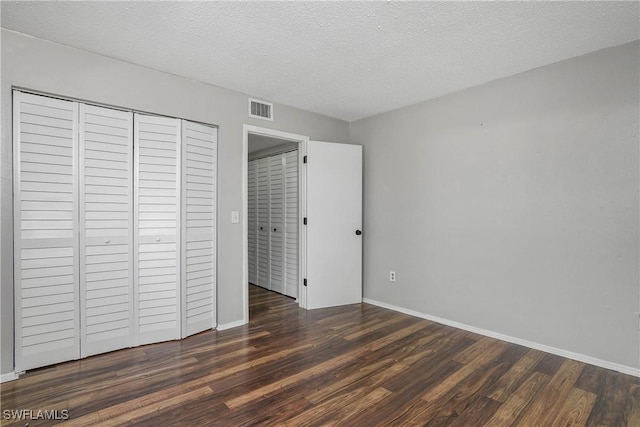 unfurnished bedroom featuring a closet, visible vents, a textured ceiling, wood finished floors, and baseboards