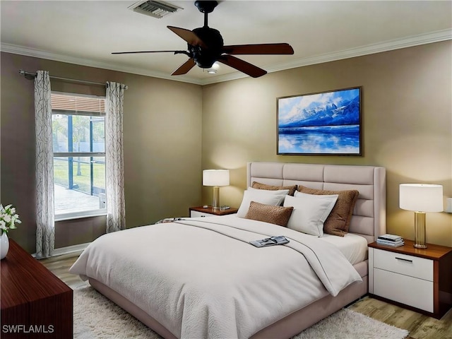 bedroom featuring light wood finished floors, a ceiling fan, visible vents, and crown molding