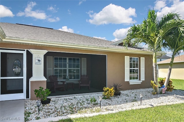 view of side of property with covered porch, roof with shingles, and stucco siding