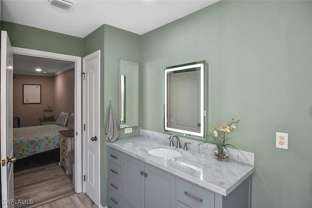 bathroom featuring vanity, wood finished floors, visible vents, and connected bathroom