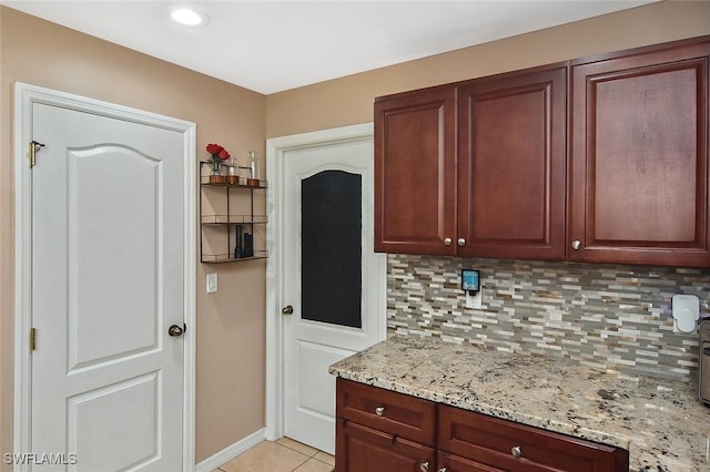 kitchen with light tile patterned floors, baseboards, backsplash, and light stone countertops