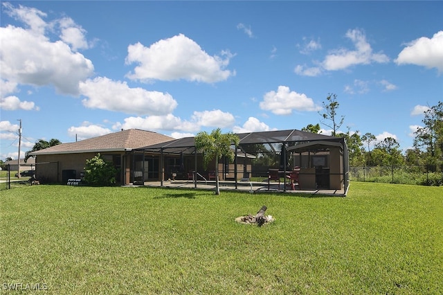 rear view of property featuring glass enclosure, fence, and a lawn