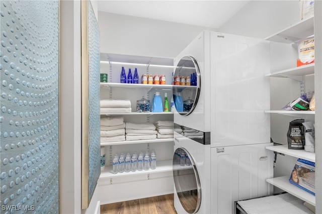 clothes washing area with stacked washer / dryer and wood finished floors