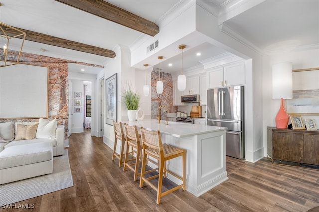 kitchen featuring beam ceiling, stainless steel appliances, visible vents, open floor plan, and a kitchen breakfast bar