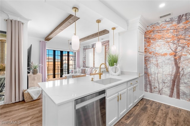 kitchen featuring open floor plan, wood finished floors, a peninsula, a sink, and stainless steel dishwasher