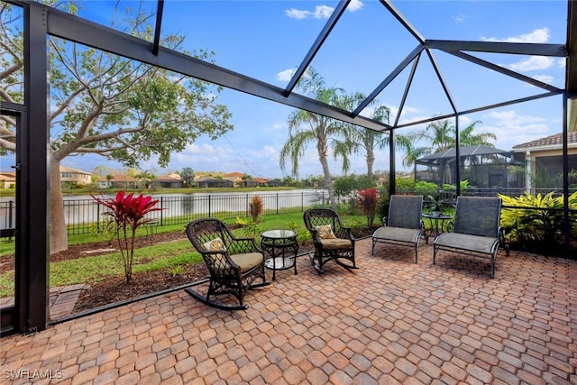 view of patio with fence private yard, glass enclosure, and a water view