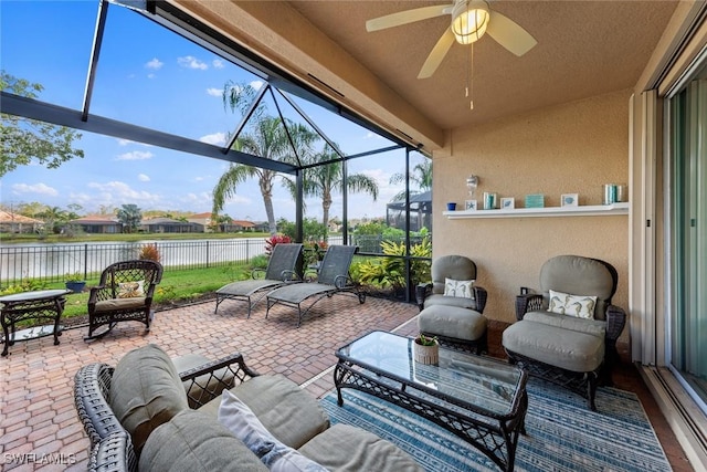 view of patio / terrace with a ceiling fan, a water view, a lanai, fence, and an outdoor living space