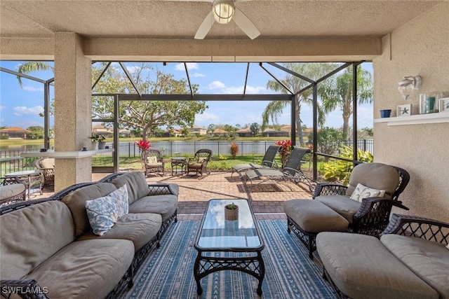 view of patio / terrace featuring a ceiling fan, glass enclosure, a water view, fence, and an outdoor living space