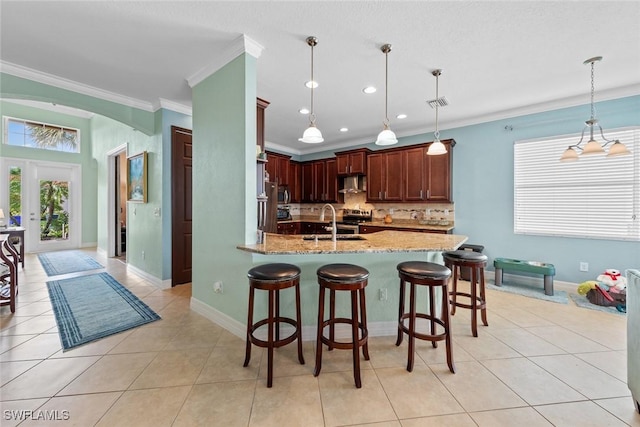 kitchen with light tile patterned floors, arched walkways, light stone countertops, crown molding, and backsplash