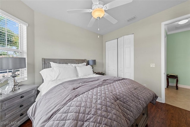 bedroom featuring a closet, visible vents, ceiling fan, wood finished floors, and baseboards