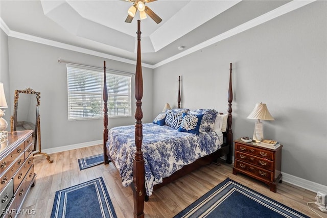 bedroom featuring light wood-style floors, baseboards, and a tray ceiling