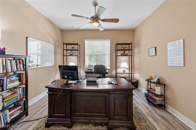 office space featuring baseboards, light wood-style flooring, and a ceiling fan