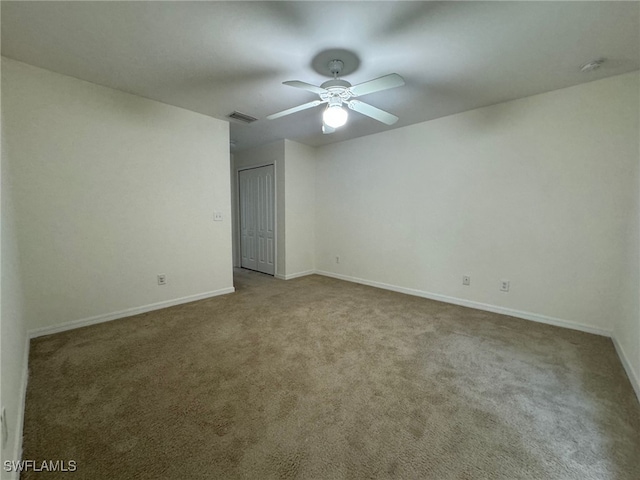 carpeted empty room with visible vents, ceiling fan, and baseboards