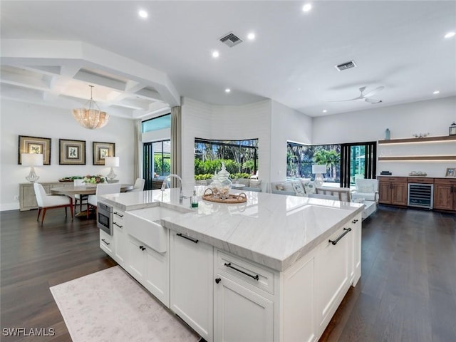 kitchen with dark wood-style flooring, visible vents, open floor plan, and a sink