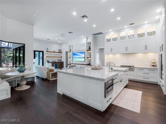 kitchen featuring dark wood finished floors, visible vents, white cabinets, a sink, and light stone countertops