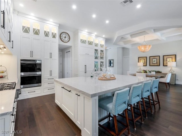 kitchen featuring a large island, visible vents, dark wood-type flooring, stainless steel double oven, and white cabinets