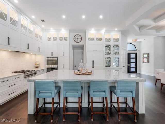 kitchen with appliances with stainless steel finishes, visible vents, white cabinetry, and backsplash