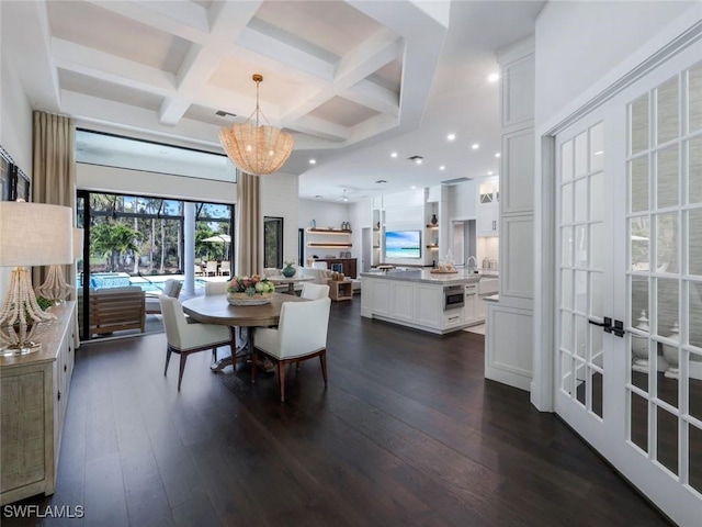 dining room featuring dark wood-type flooring, beam ceiling, coffered ceiling, and an inviting chandelier