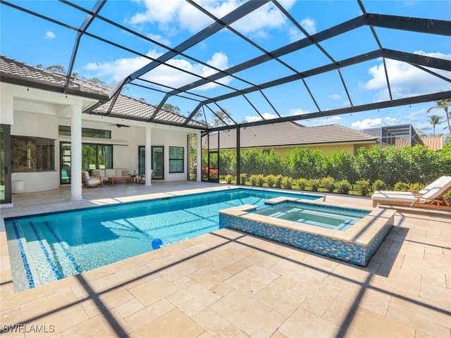 view of swimming pool with glass enclosure, a pool with connected hot tub, ceiling fan, and a patio