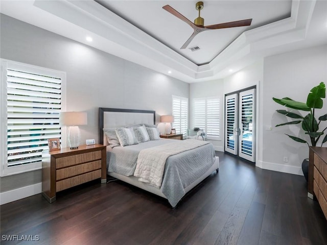 bedroom with baseboards, visible vents, dark wood-type flooring, access to outside, and a tray ceiling