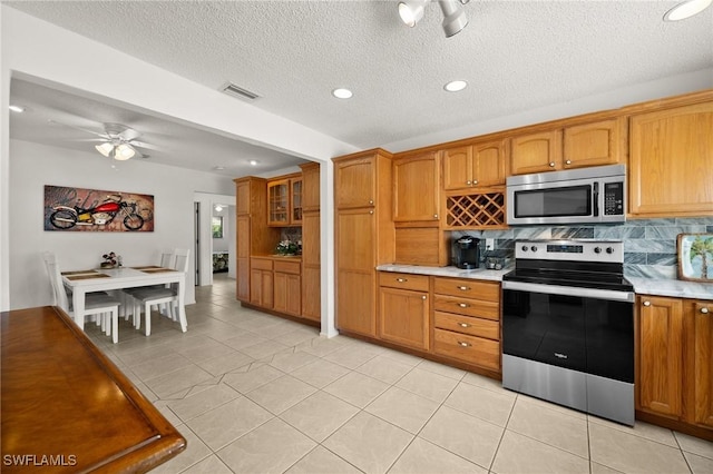 kitchen with visible vents, appliances with stainless steel finishes, brown cabinets, and light countertops