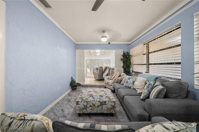 living area with visible vents, a textured wall, ornamental molding, ceiling fan, and baseboards